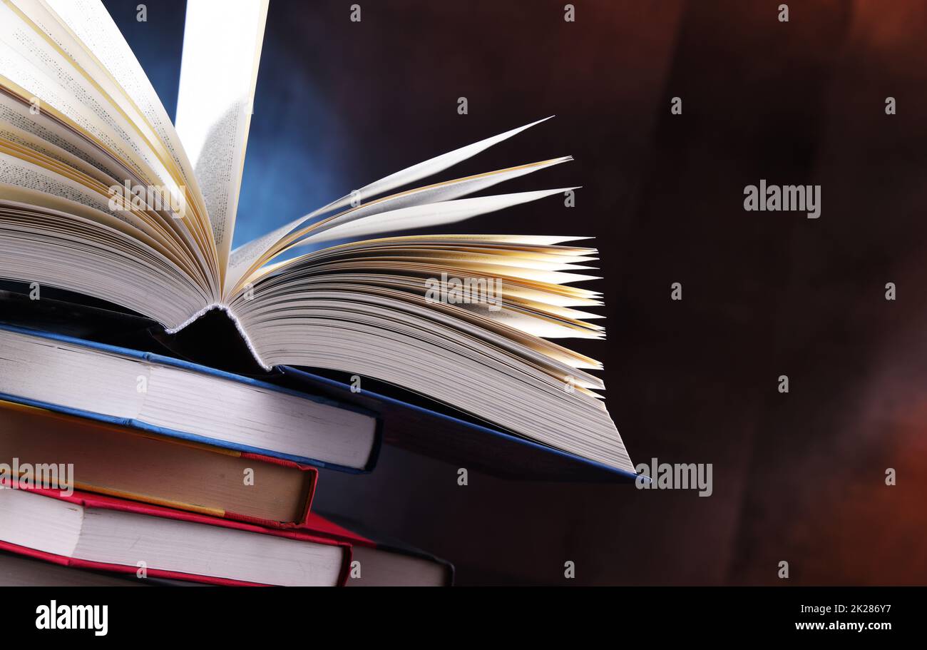 A composition with an open book lying on a stack of other books Stock Photo