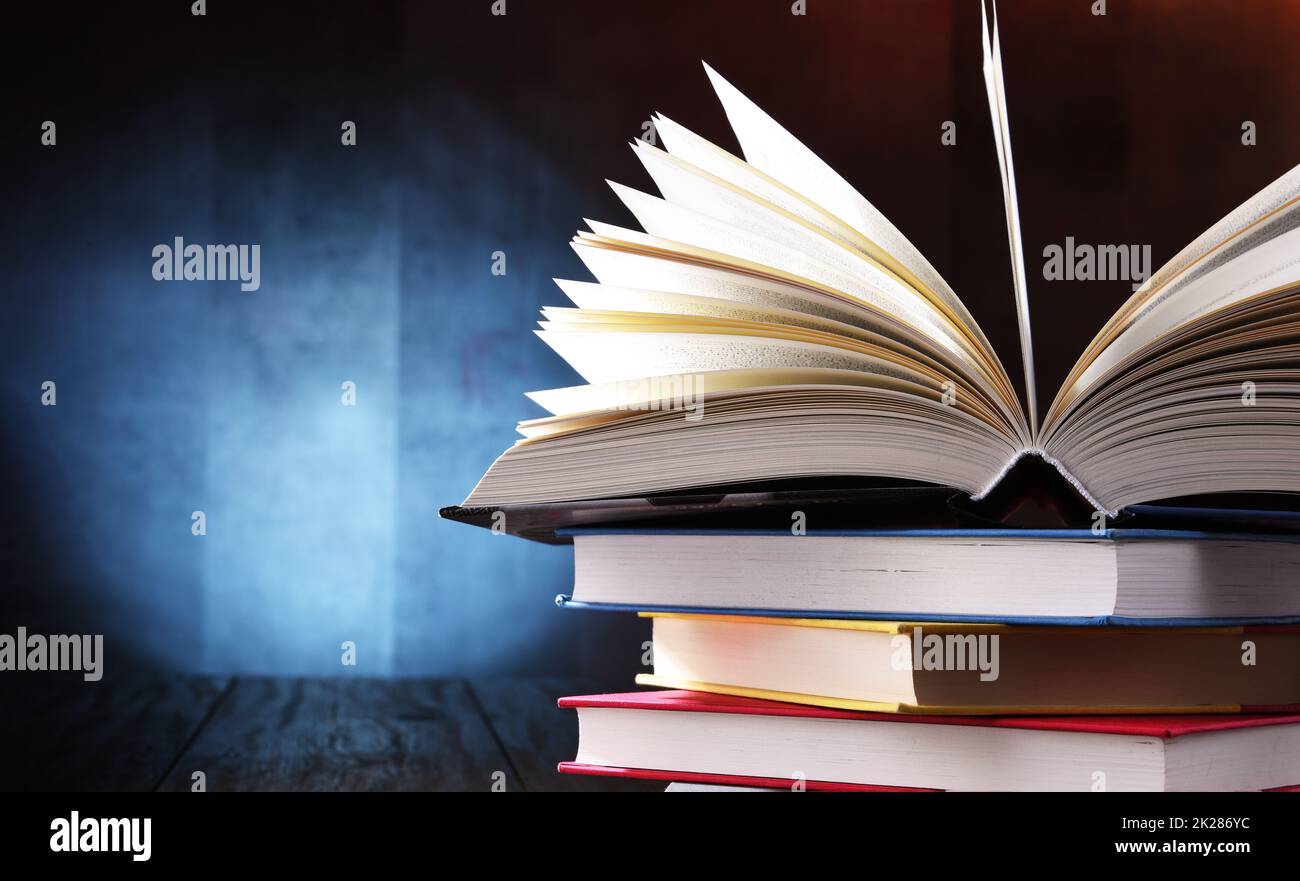 A composition with an open book lying on a stack of other books Stock Photo