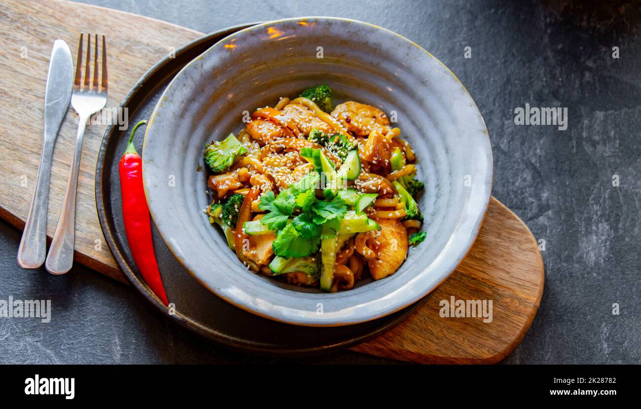 A bowl of udon with chicken and broccoli Stock Photo