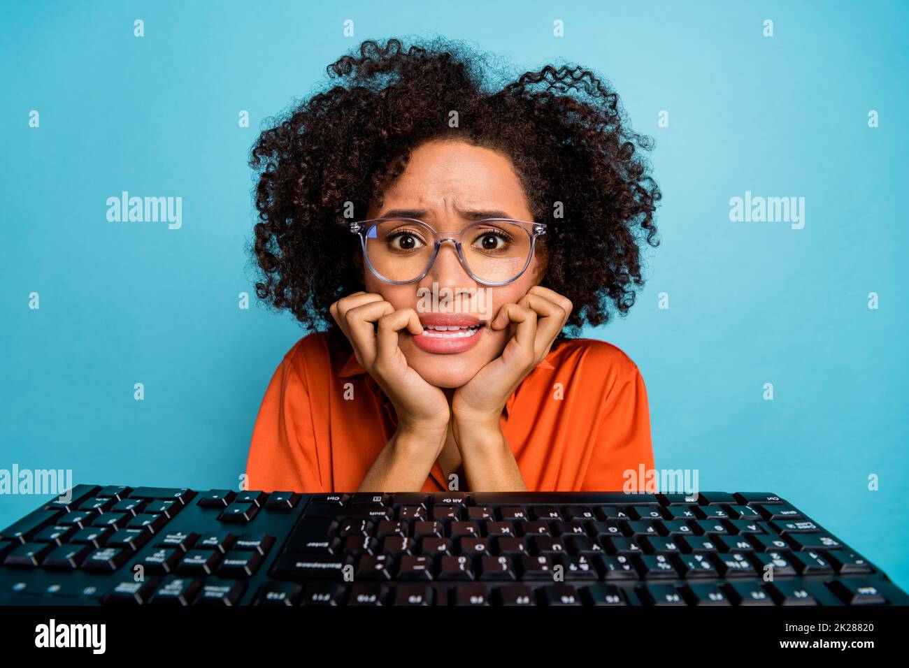 Portrait of attractive worried desperate wavy-haired girl nerd studying biting nails isolated on bright blue color background Stock Photo