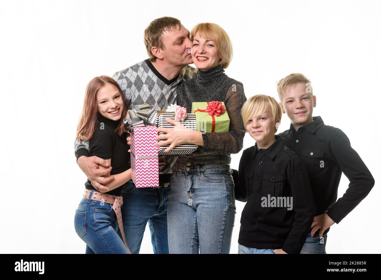 Children and dad congratulated mom on her birthday by giving her gifts, dad kisses mom Stock Photo