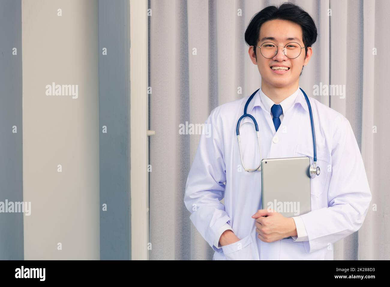 Doctor man smiling in uniform and stethoscope neck strap tablet on hand Stock Photo
