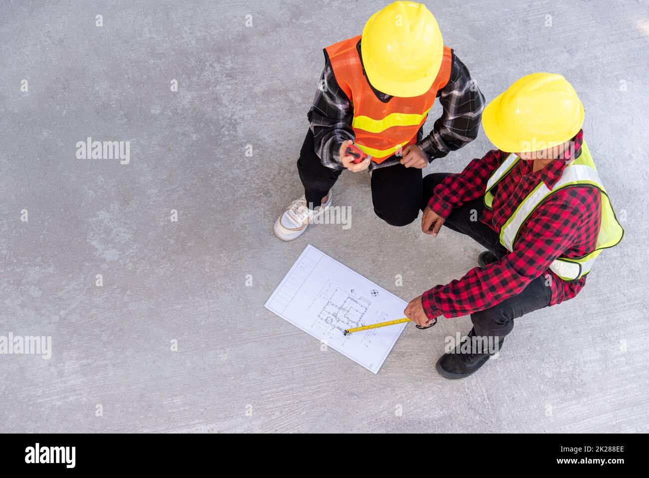 Architect and client discuss help create plan with blueprint of the building at construction site floor Stock Photo