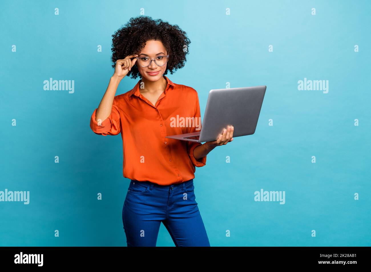 Portrait of beautiful trendy intellectual wavy-haired girl geek nerd using laptop analyzing isolated on vivid blue color background Stock Photo