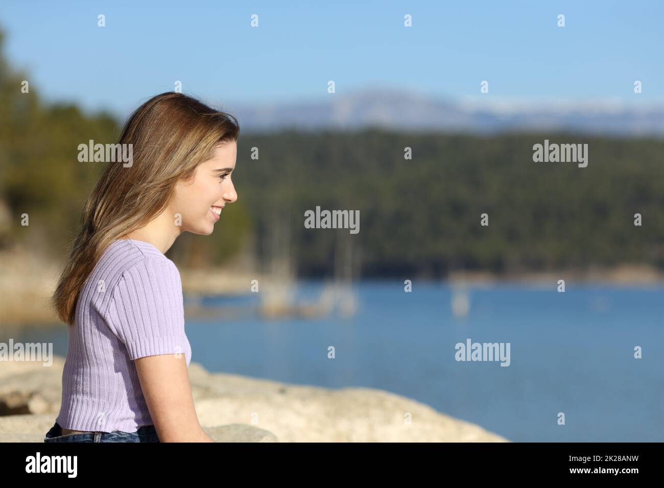 Happy teen contemplating a lake view in nature Stock Photo
