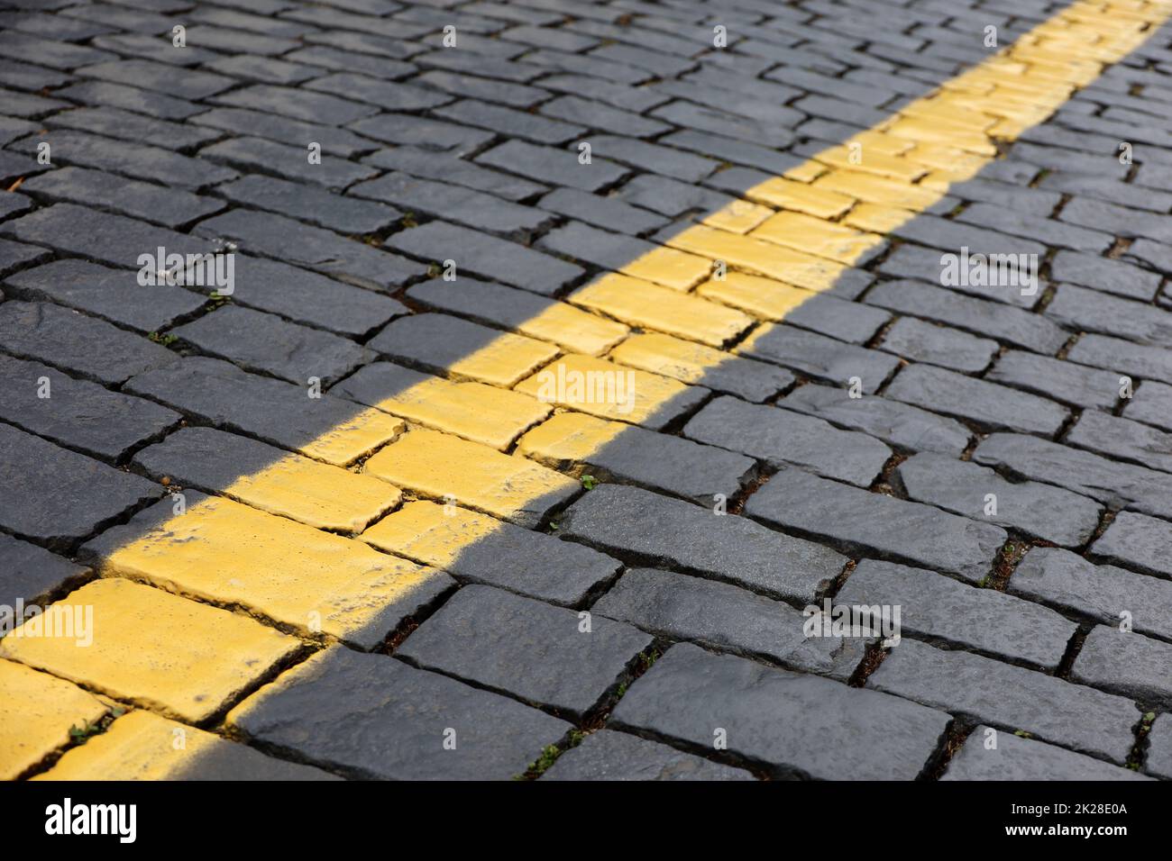 Stone pavement texture, cobbled street. Road marking, yellow line on tiles Stock Photo