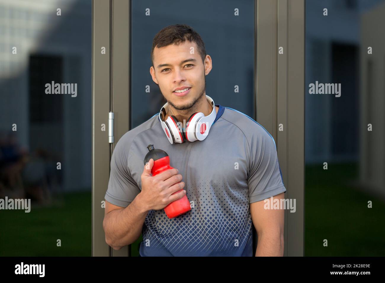 Smiling young latin man water bottle runner outdoor sports fitness training Stock Photo