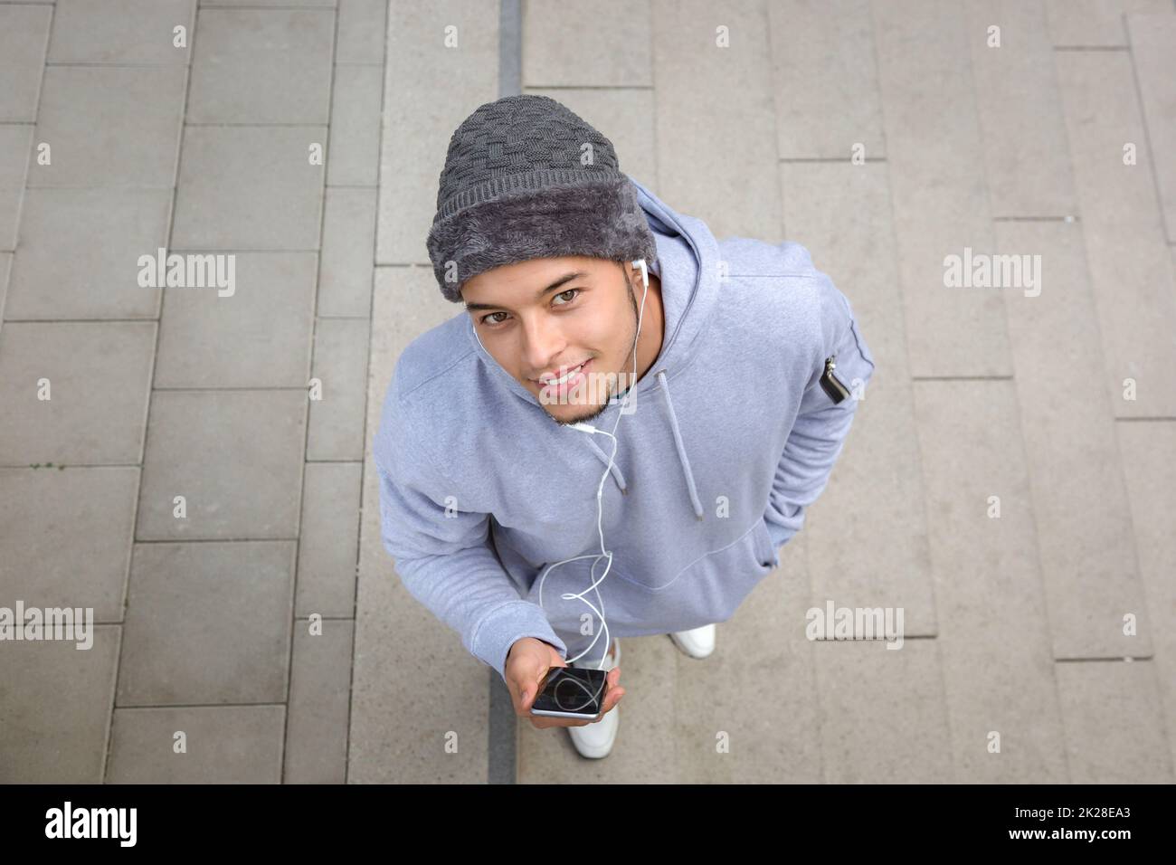 Listening to music smiling young latin man looking into camera runner sports training from above Stock Photo