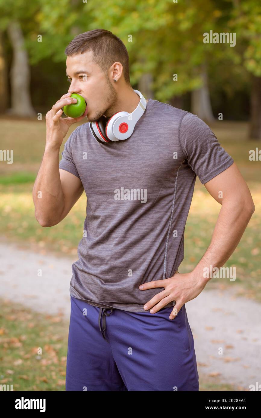 Young man eating an apple runner portrait format sports training workout fitness Stock Photo