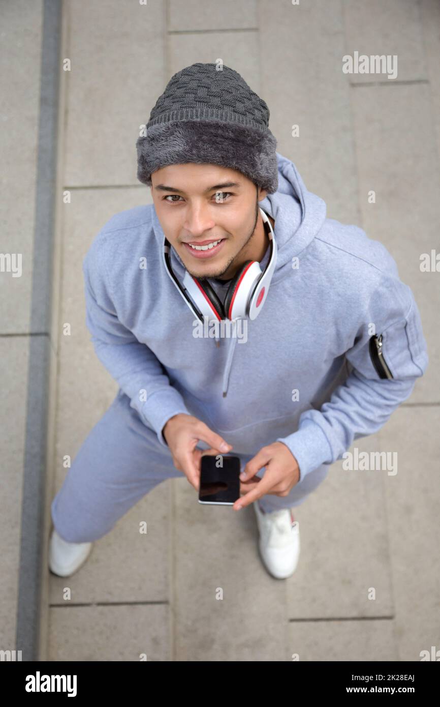 Listening to music smiling young latin man runner portrait format sports training from above Stock Photo