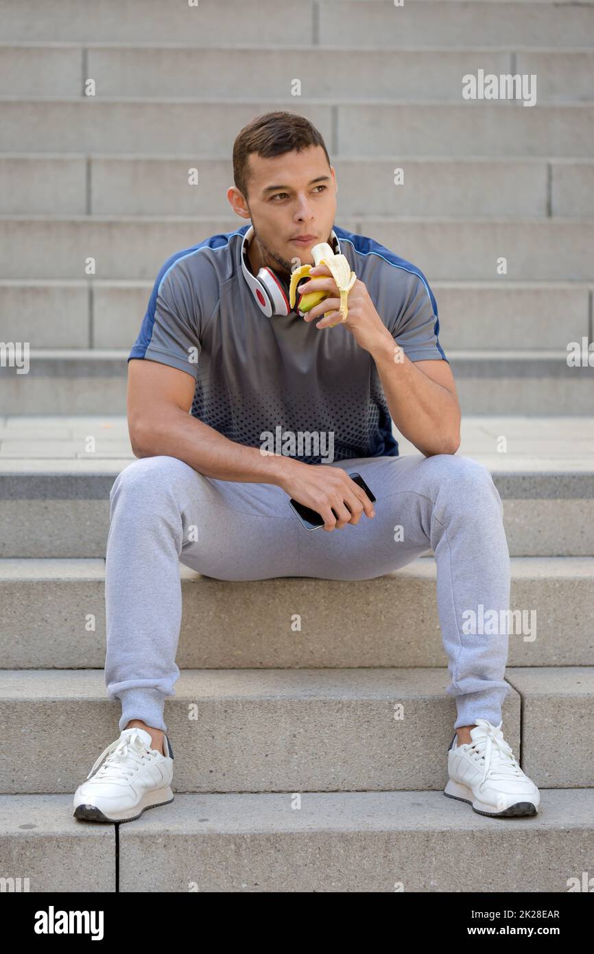 Young latin man eating banana fruit runner fitness portrait format sports training Stock Photo