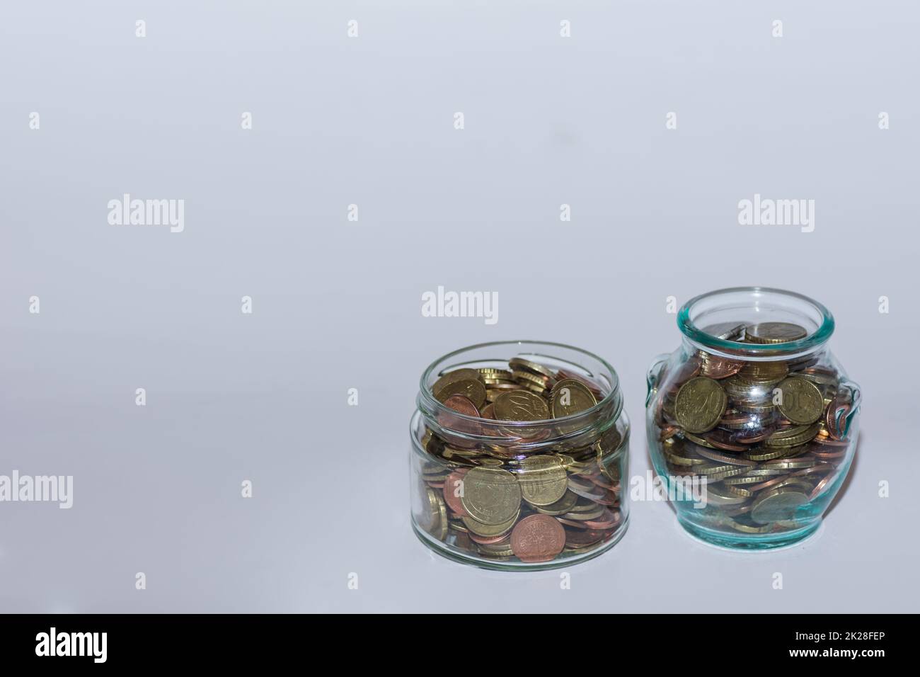 saved money in two  jars with many different euro coins for financial independence view Stock Photo