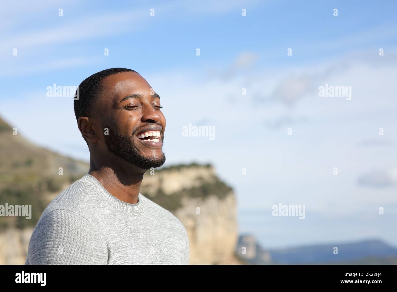 Funny man with black skin laughing outdoors Stock Photo