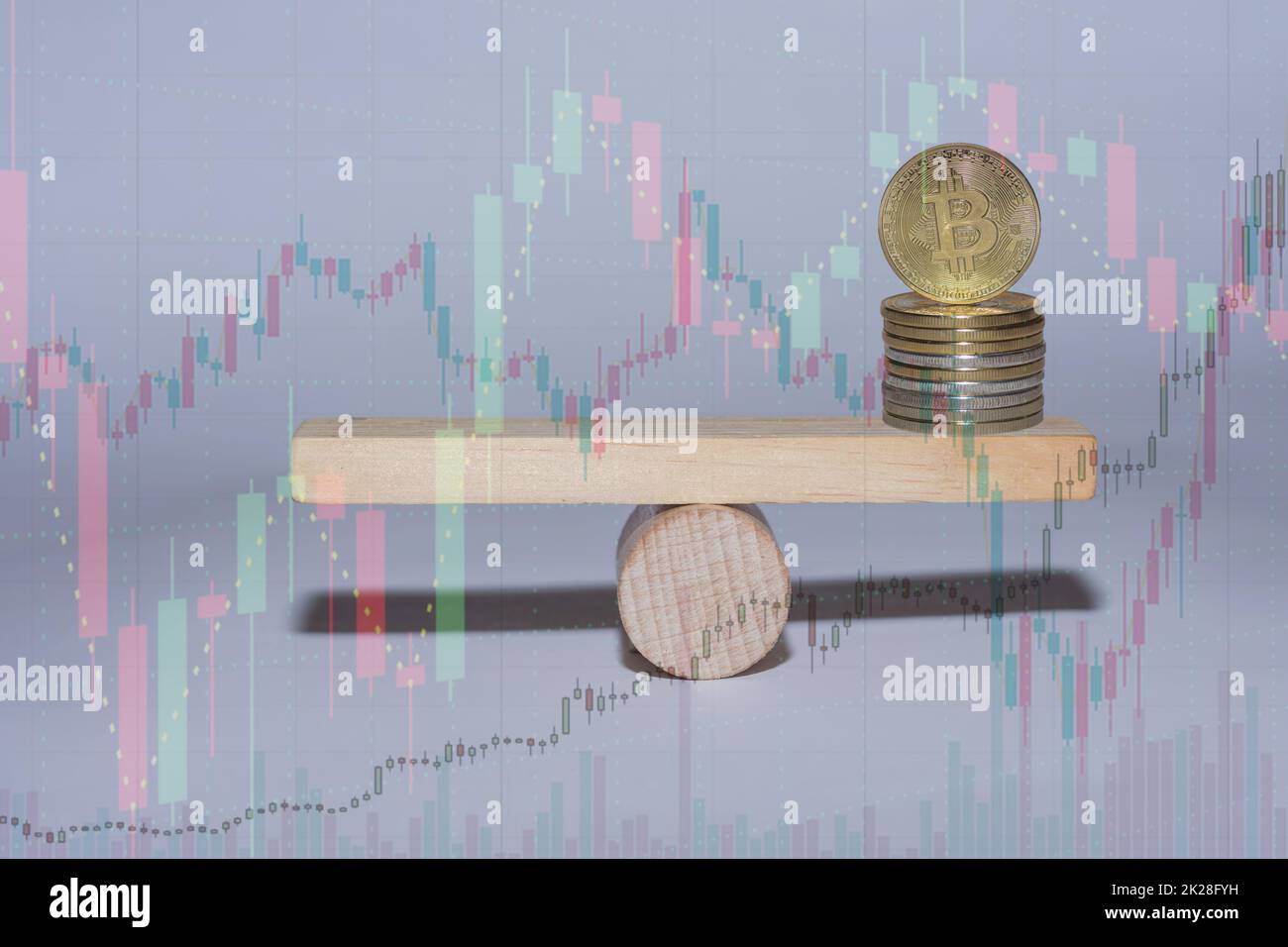 stacked bitcoin on a wooden seesaw with charts from the market Stock Photo