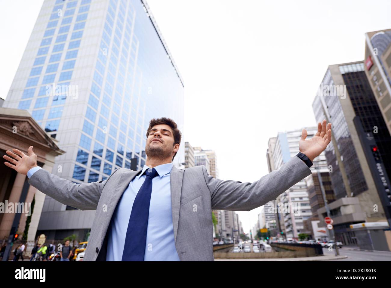 Theres no place like the city. A contented young businessman standing in the city with his eyes closed and his arms raised. Stock Photo