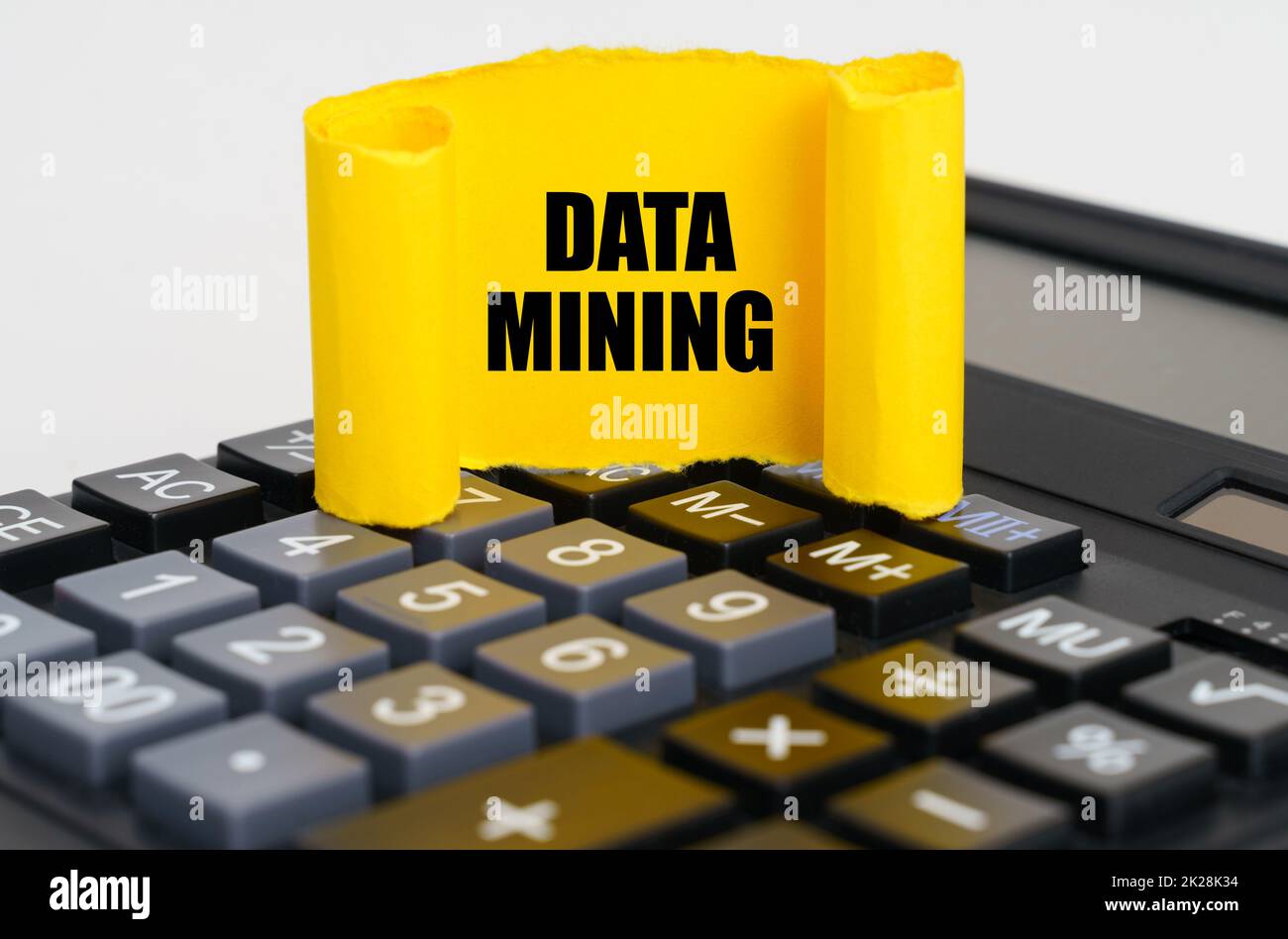 Business concept. On the calculator is a yellow, twisted paper plate with the inscription - DATA MINING Stock Photo