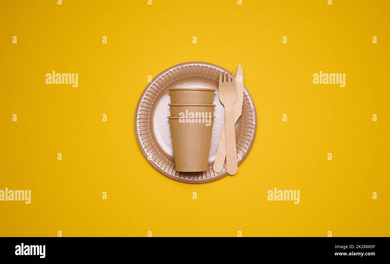 brown paper cups and plates on a yellow background. Recyclable garbage