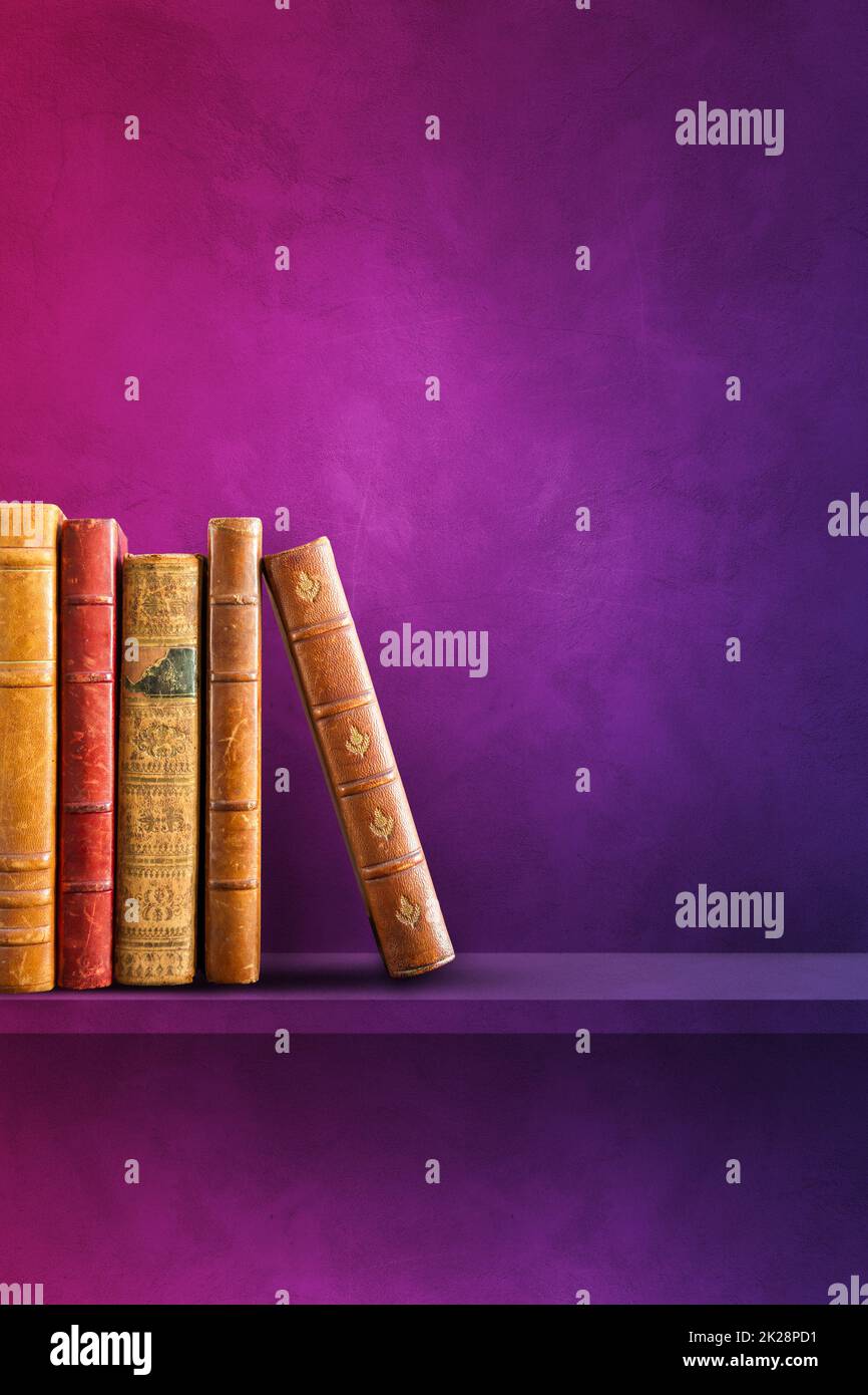 Row of old books on purple shelf. Vertical background Stock Photo