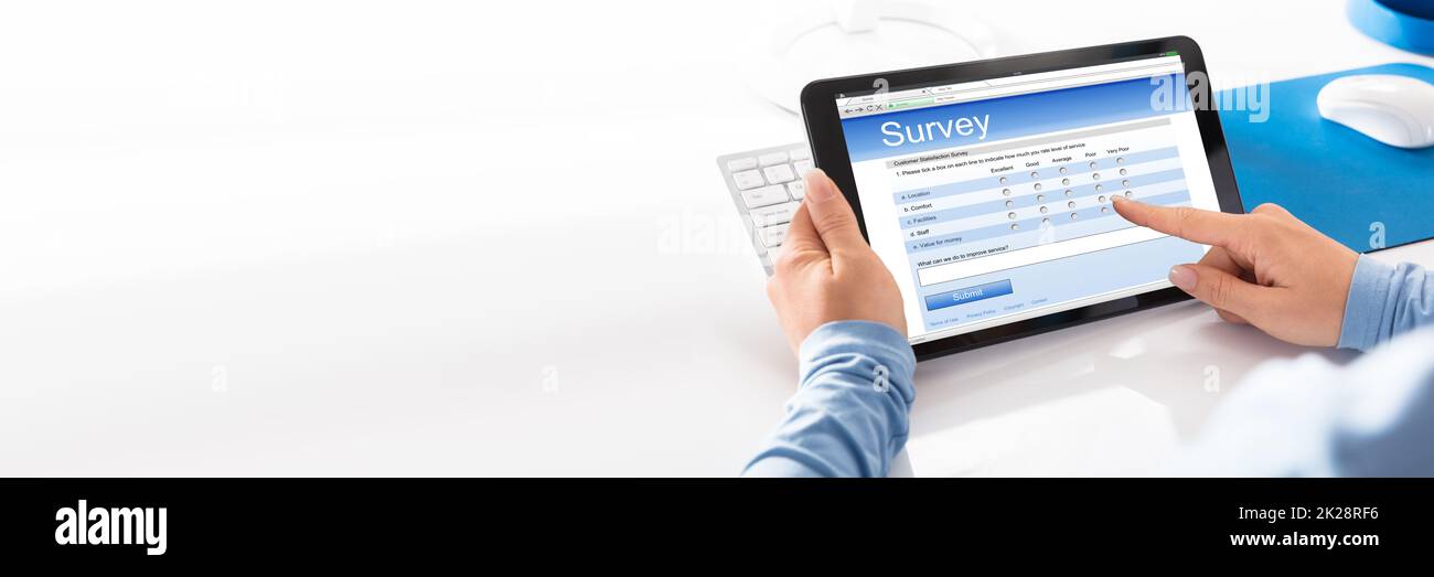 Woman Filling Online Survey Form On Tablet Computer Stock Photo
