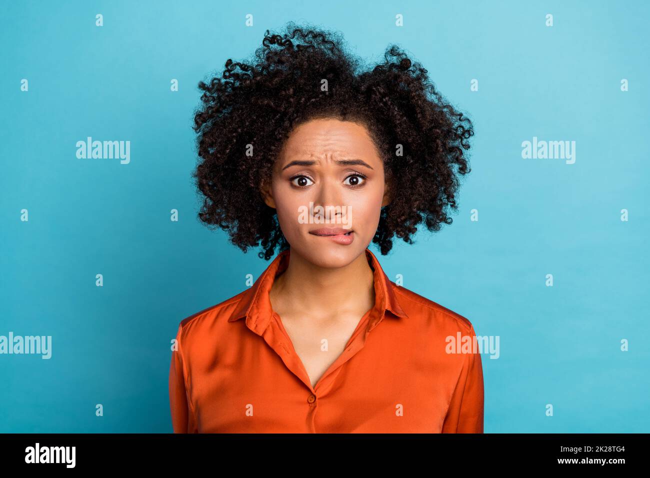 Photo of puzzled scared lady biting lip look camera wear silky shirt isolated on blue color background Stock Photo