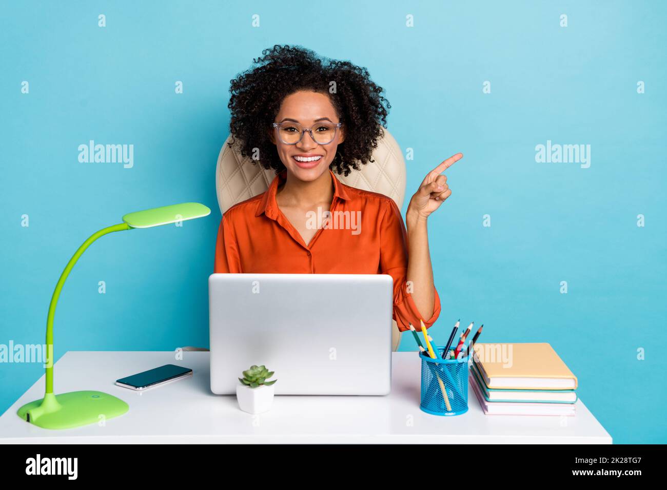 Photo of dreamy lady dressed orange shirt glasses pointing empty space working modern device isolated blue color background Stock Photo