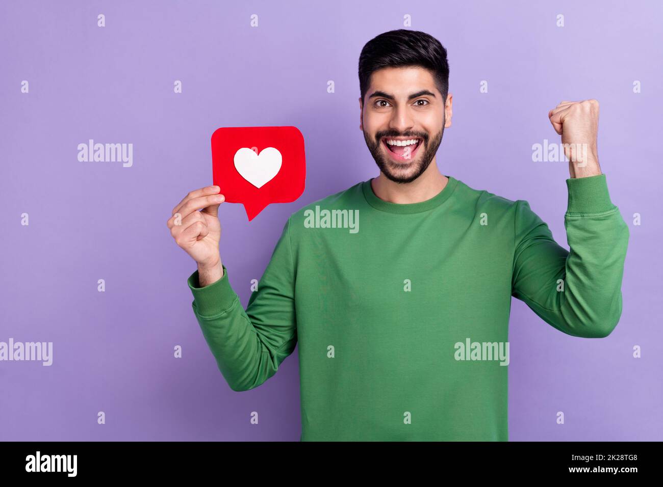 Photo of handsome positive cheerful satisfied guy wear green pullover scream yes hold fist got like isolated on violet color background Stock Photo