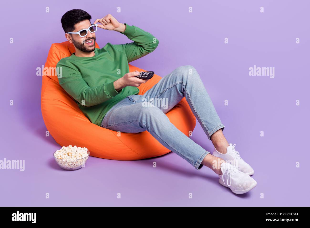 Full length photo of young hispanic guy watching television switch channels dressed trendy green look isolated on violet color background Stock Photo