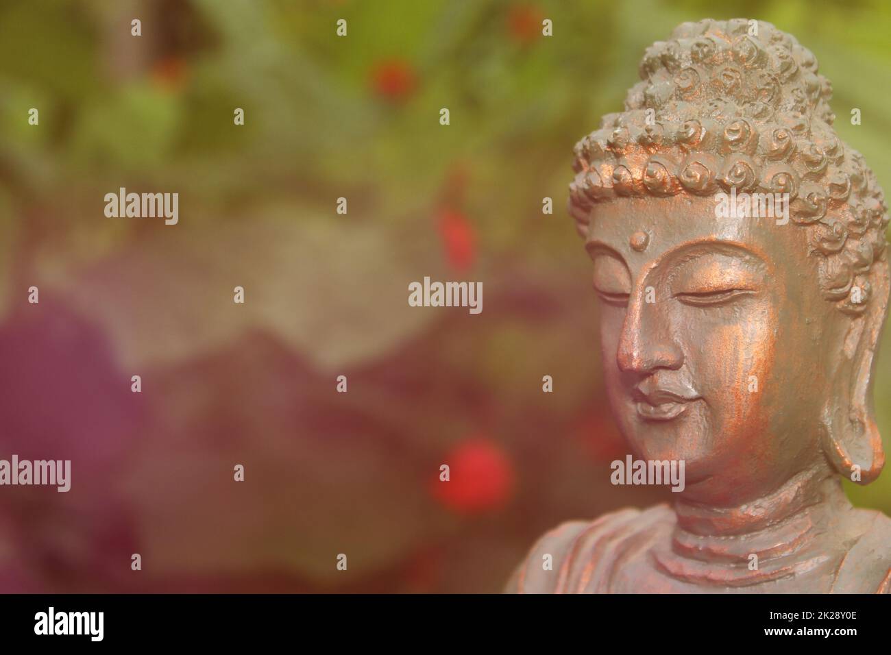 Buddha Statue in Garden with blurred flowers in background Stock Photo