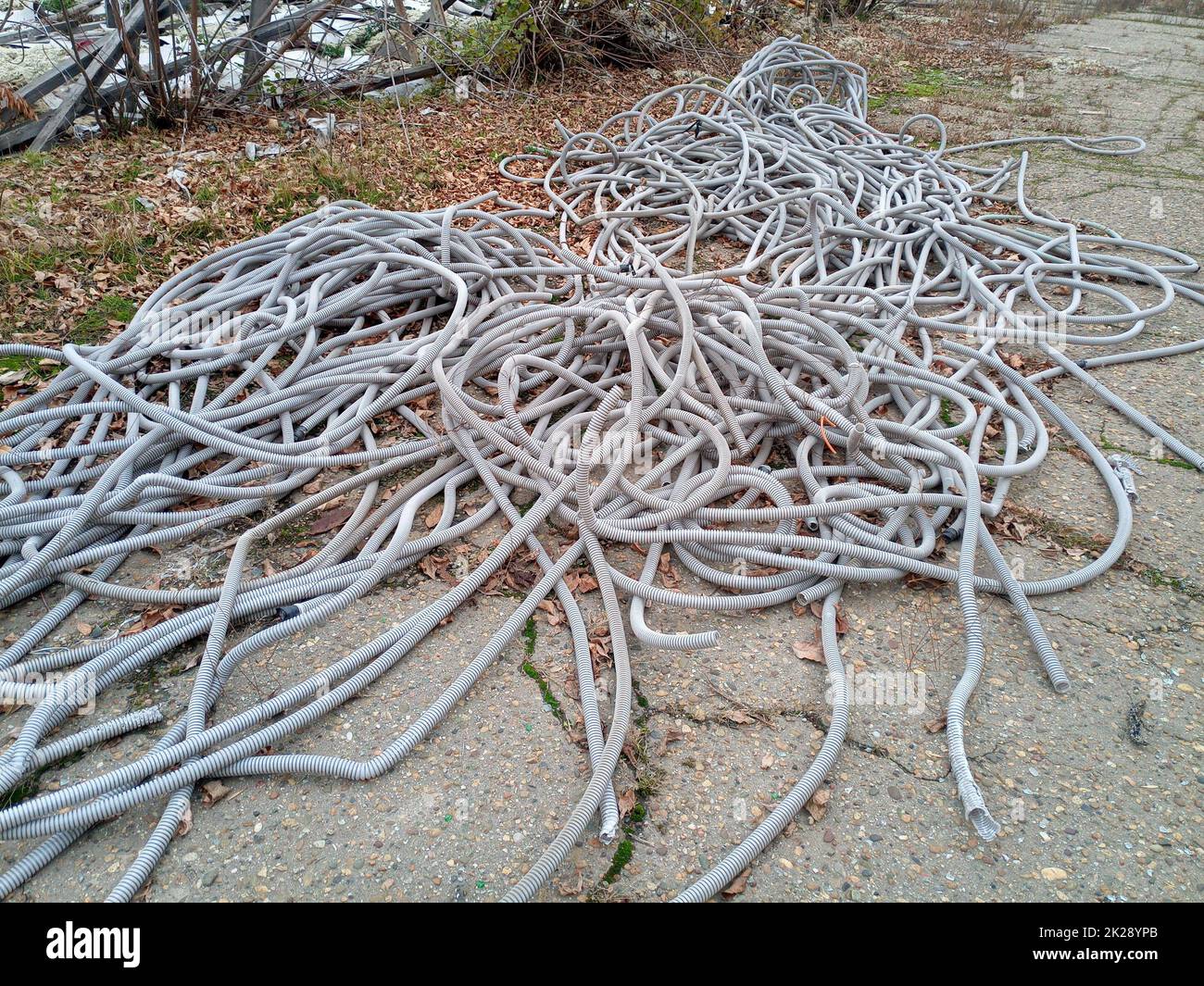 Corrugated pipes for electrical wiring lie in heap on the ground. Stock Photo