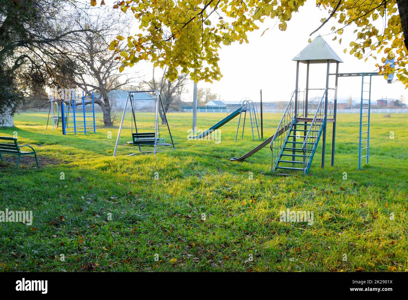 Children's playground near the stadium on the background of sunset. Swings, slide and ladder