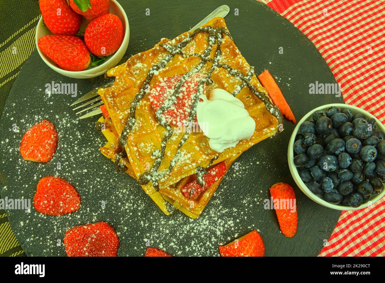 Homemade Belgian waffles with berries on slate background. Melted