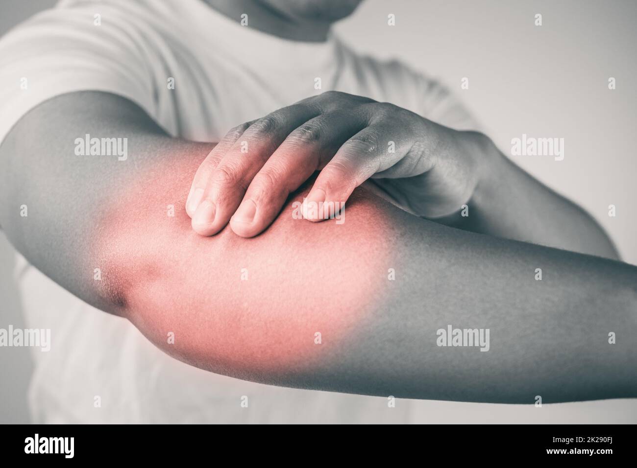 Elbow injury from tennis and golf. The man uses fingers to massage his arm. Pain symptom area is shown with red color. Healthcare knowledge. Medium close up shot with copy space. Black and white tone. Stock Photo