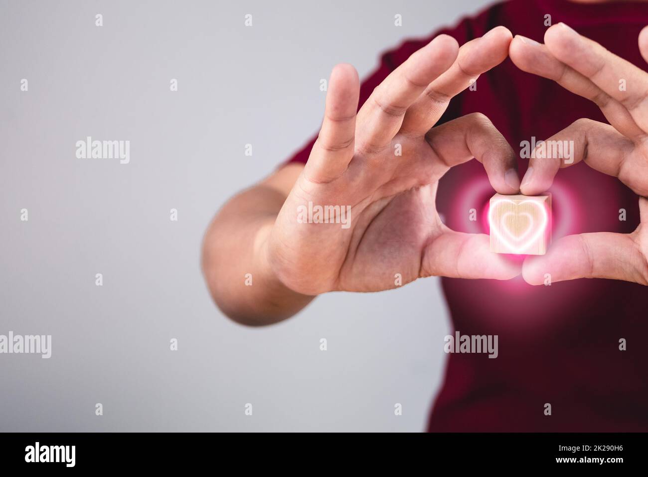 Person shows hands sign of love with heart visual effect. The man with red shirt in medium close up shot. Valentine's concept. Copy space for messages, words and texts. Stock Photo