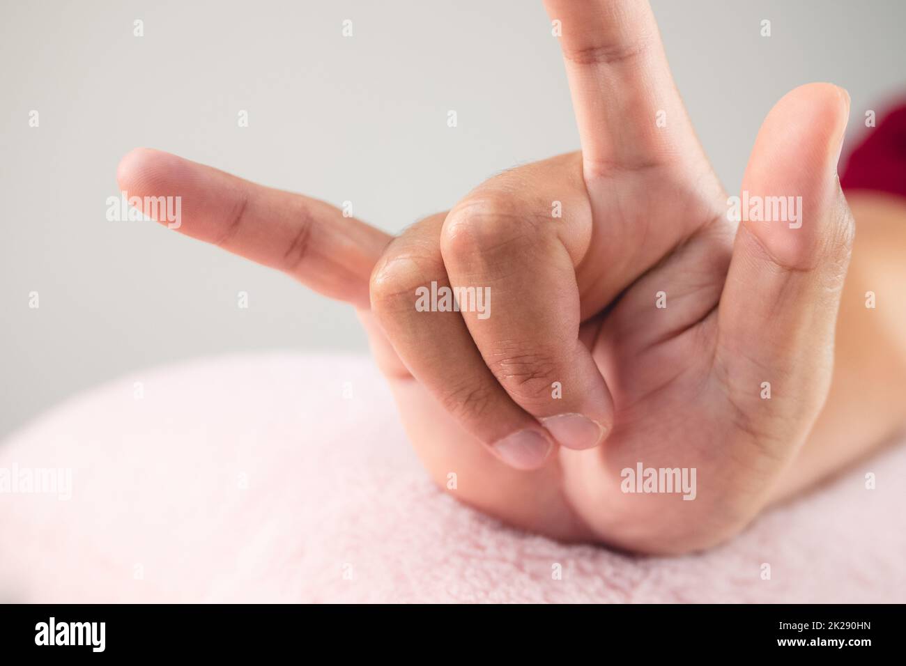 Hand with sing of Love on pink fluffy pillow. Valentine's day concept. Extreme close up shot. Stock Photo