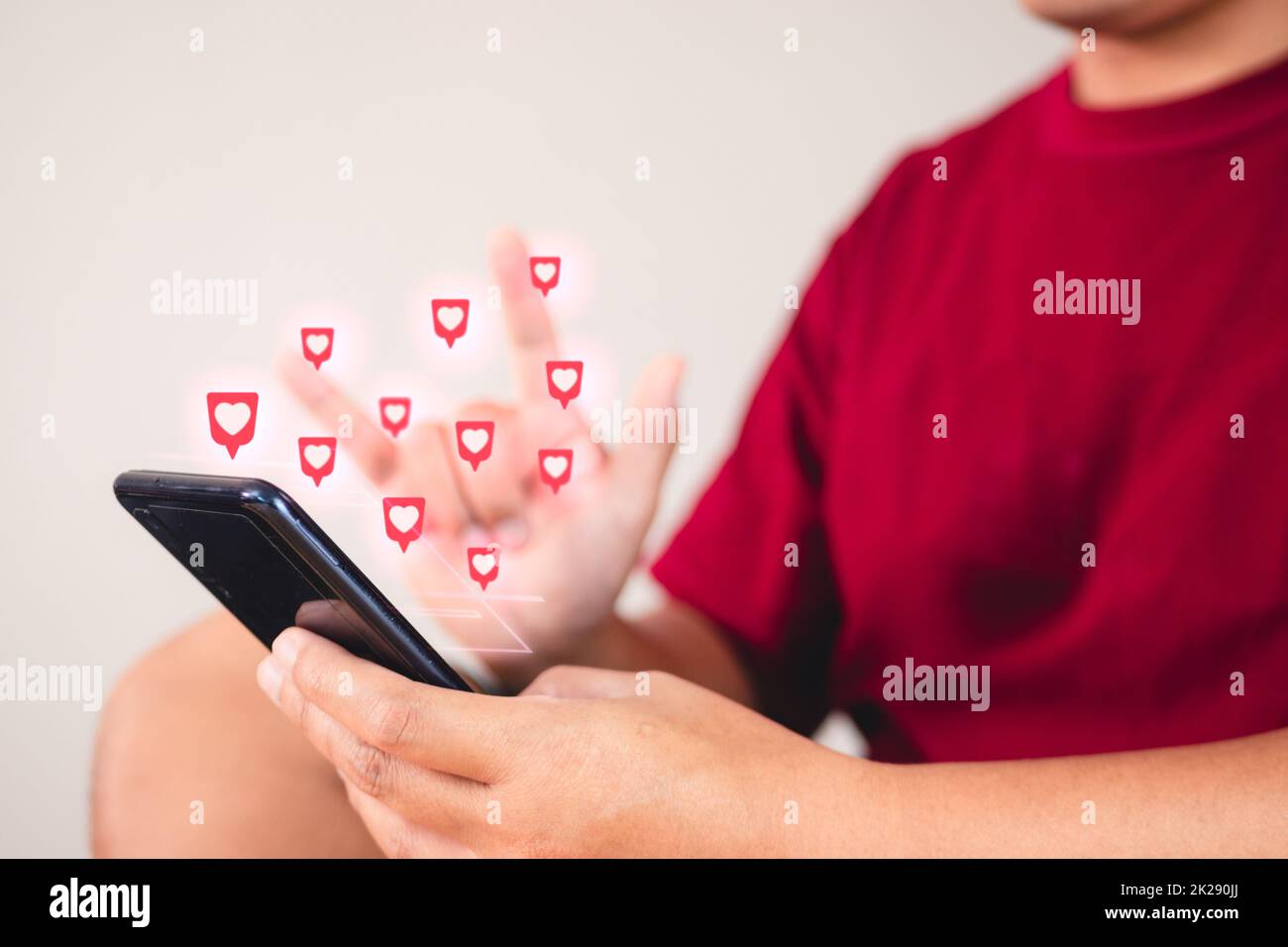 Valentine's day concept. The man uses hand sign to give love thru a smartphone. Heart shape visual effect. Stock Photo