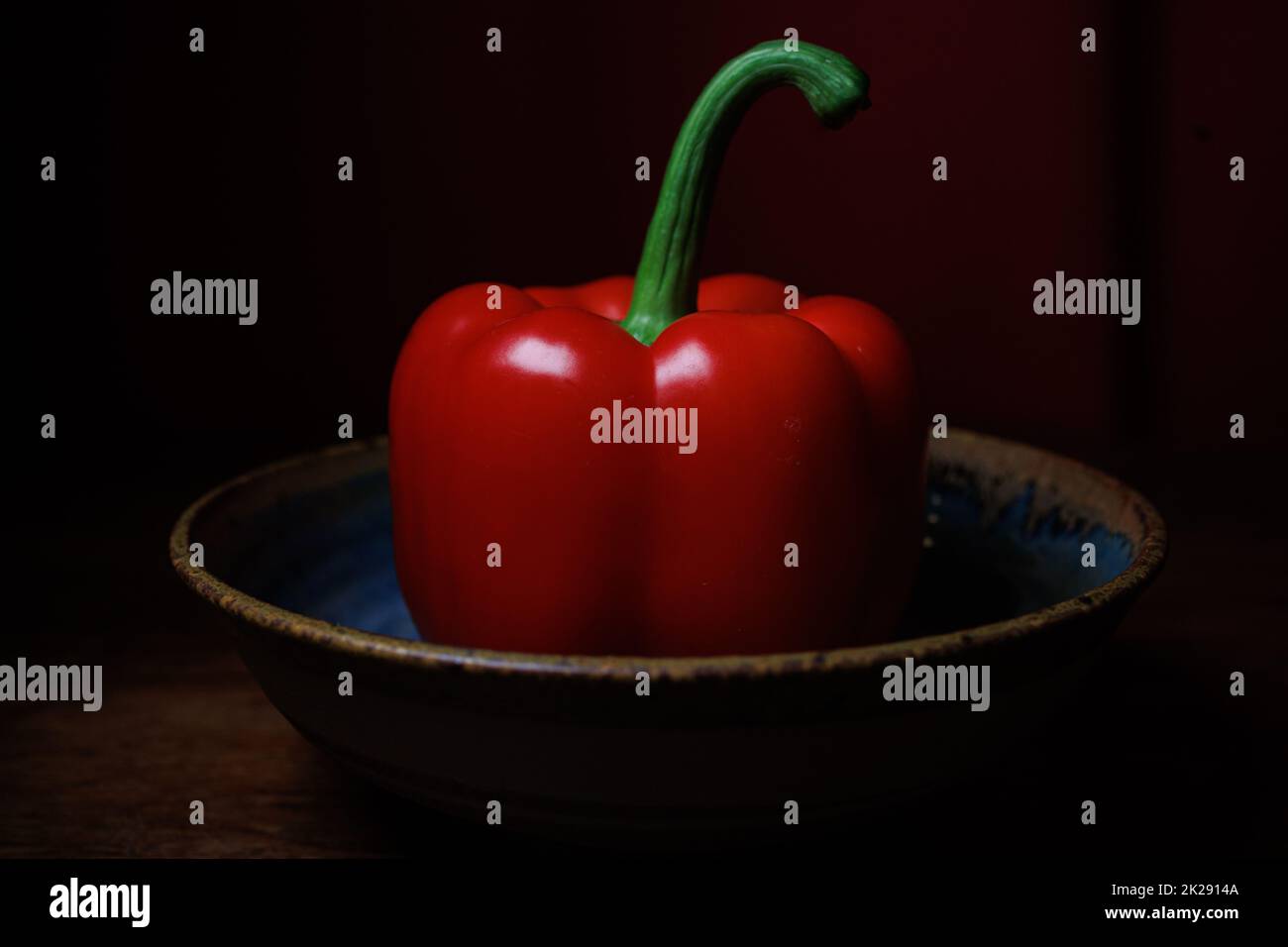 Single red pepper in handmade bowl Stock Photo
