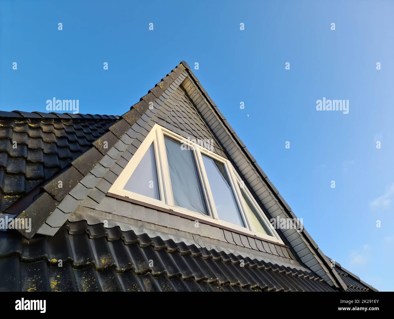 Roof window in velux style with black roof tiles. Stock Photo