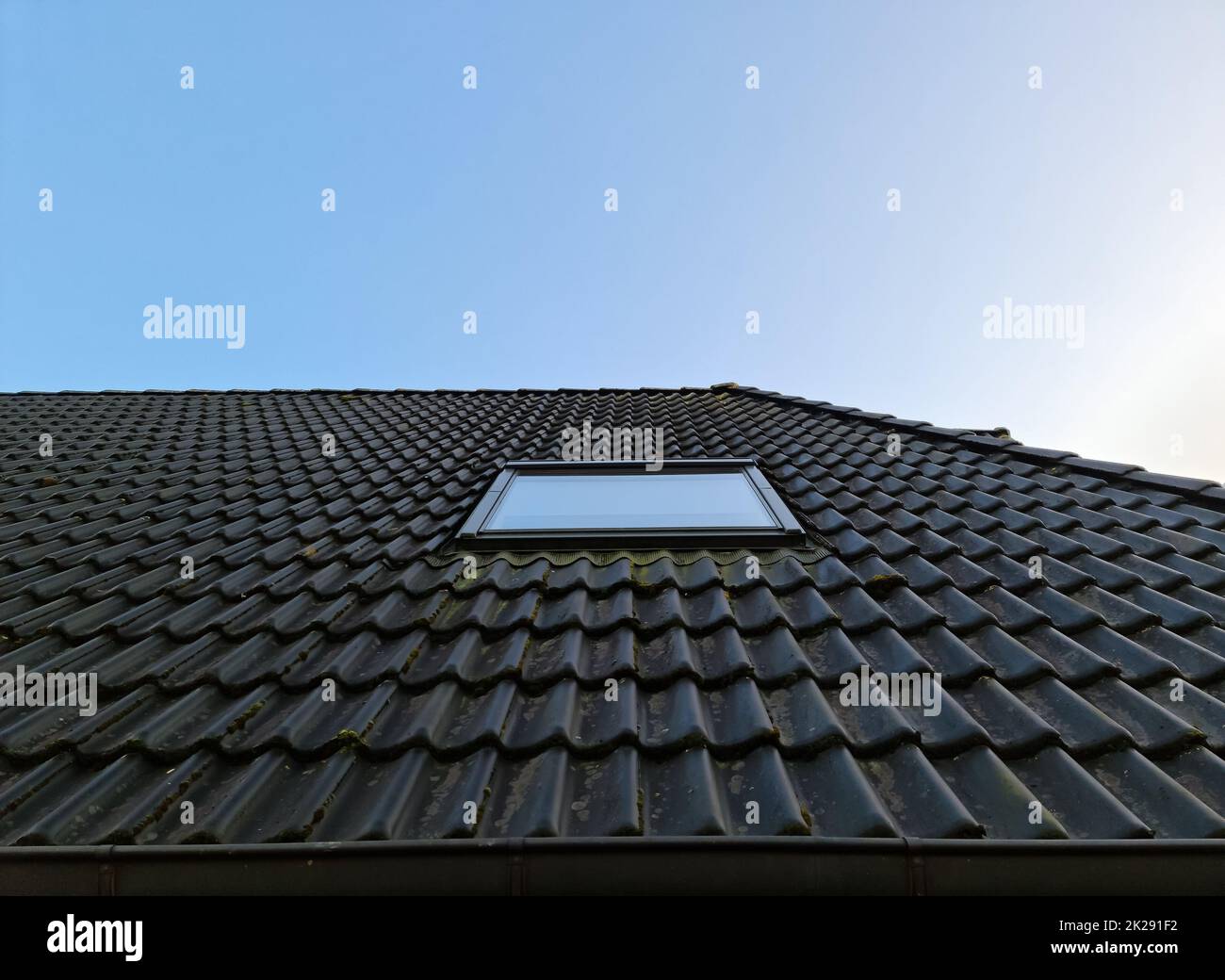 Roof window in velux style with black roof tiles. Stock Photo