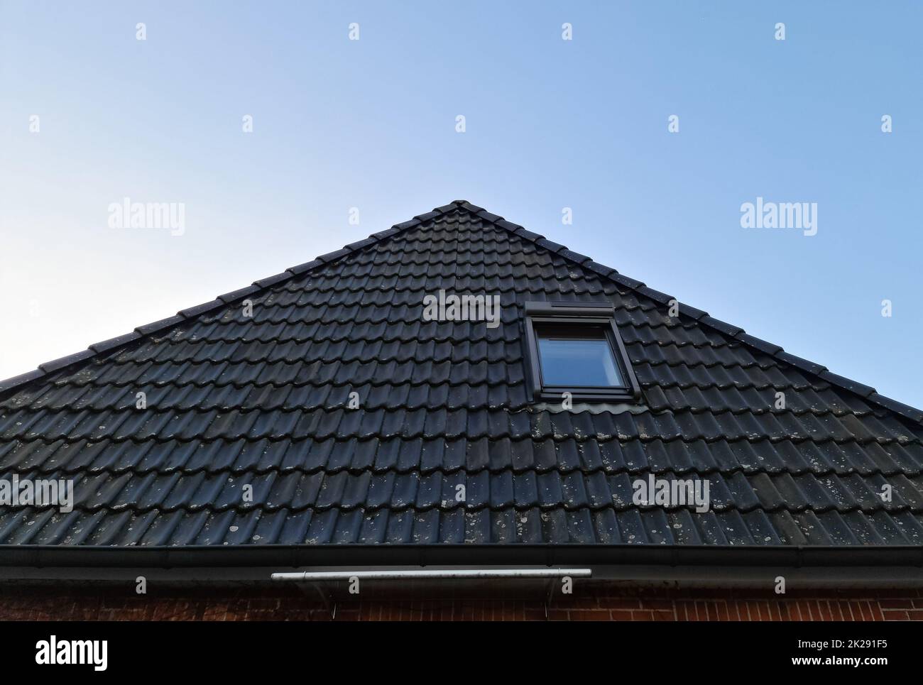 Roof window in velux style with black roof tiles. Stock Photo