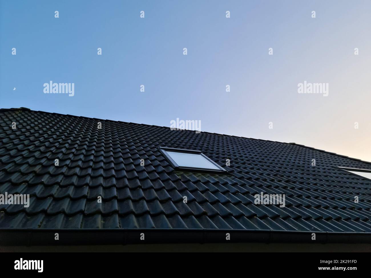 Roof window in velux style with black roof tiles. Stock Photo