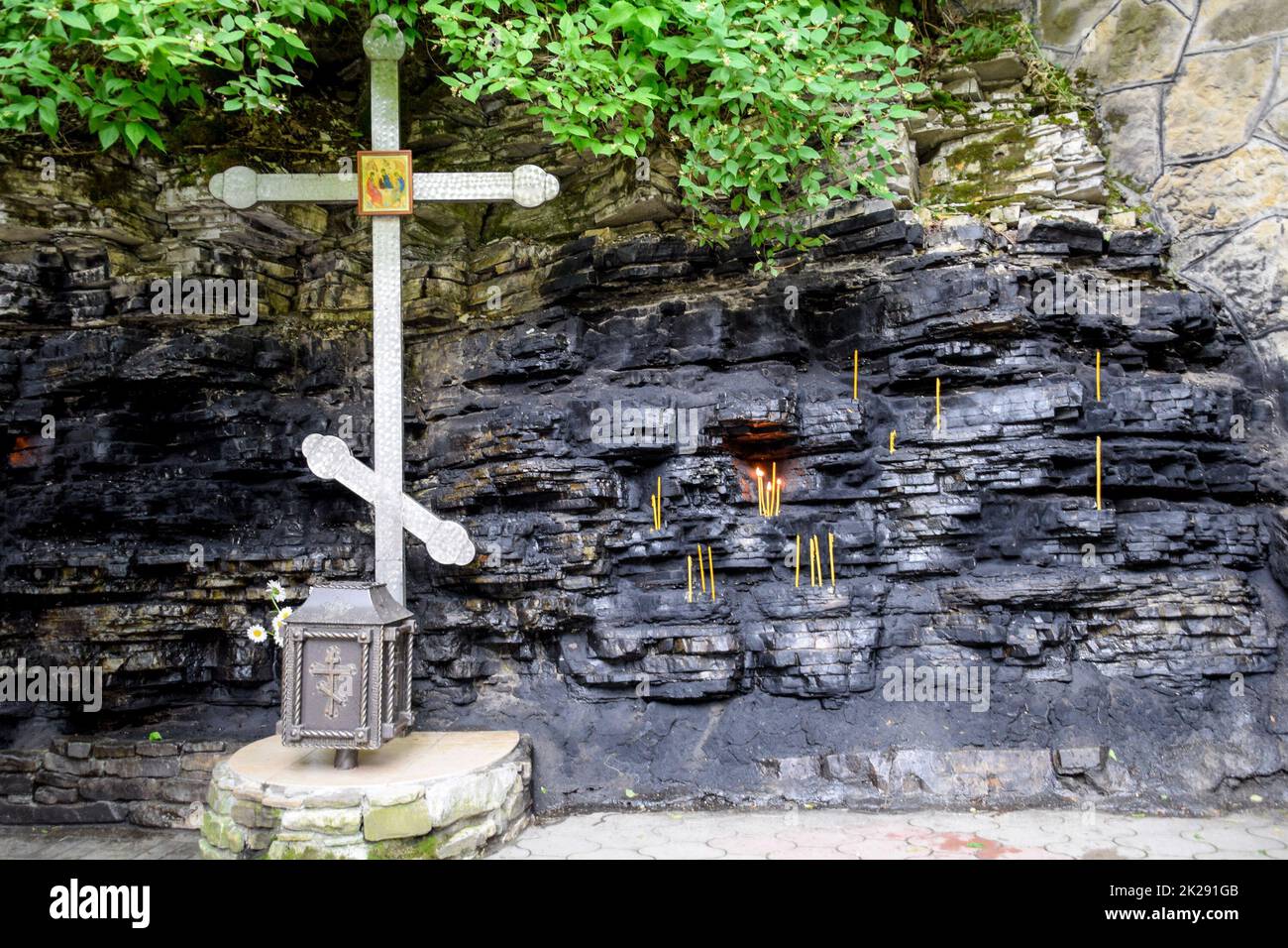Wax church candles in rock niches. Holy place Stock Photo