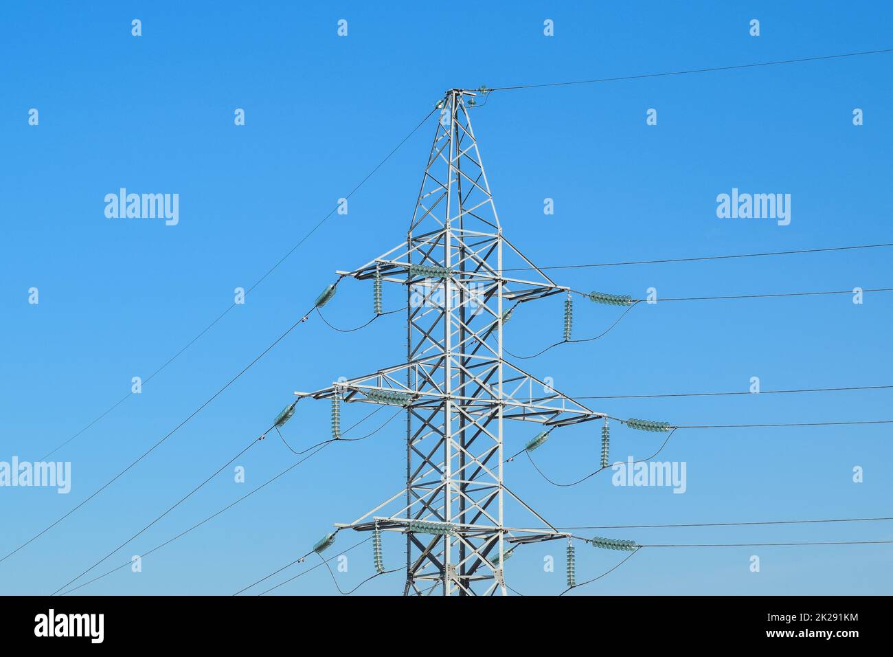 Supports high-voltage power lines against the blue sky Stock Photo - Alamy