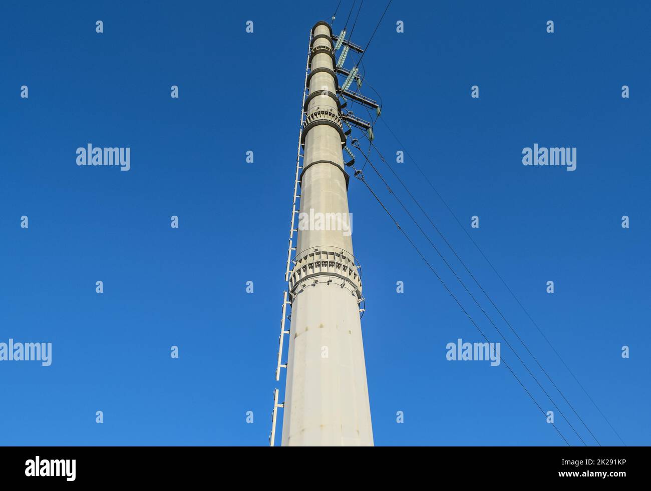Supports high-voltage power lines against the blue sky Stock Photo - Alamy