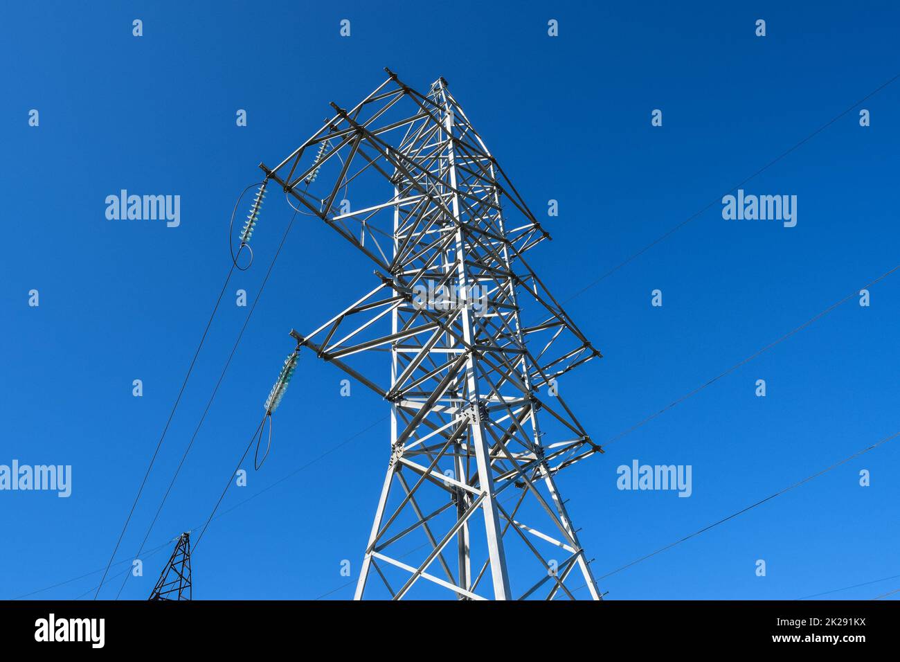 Supports high-voltage power lines against the blue sky Stock Photo - Alamy