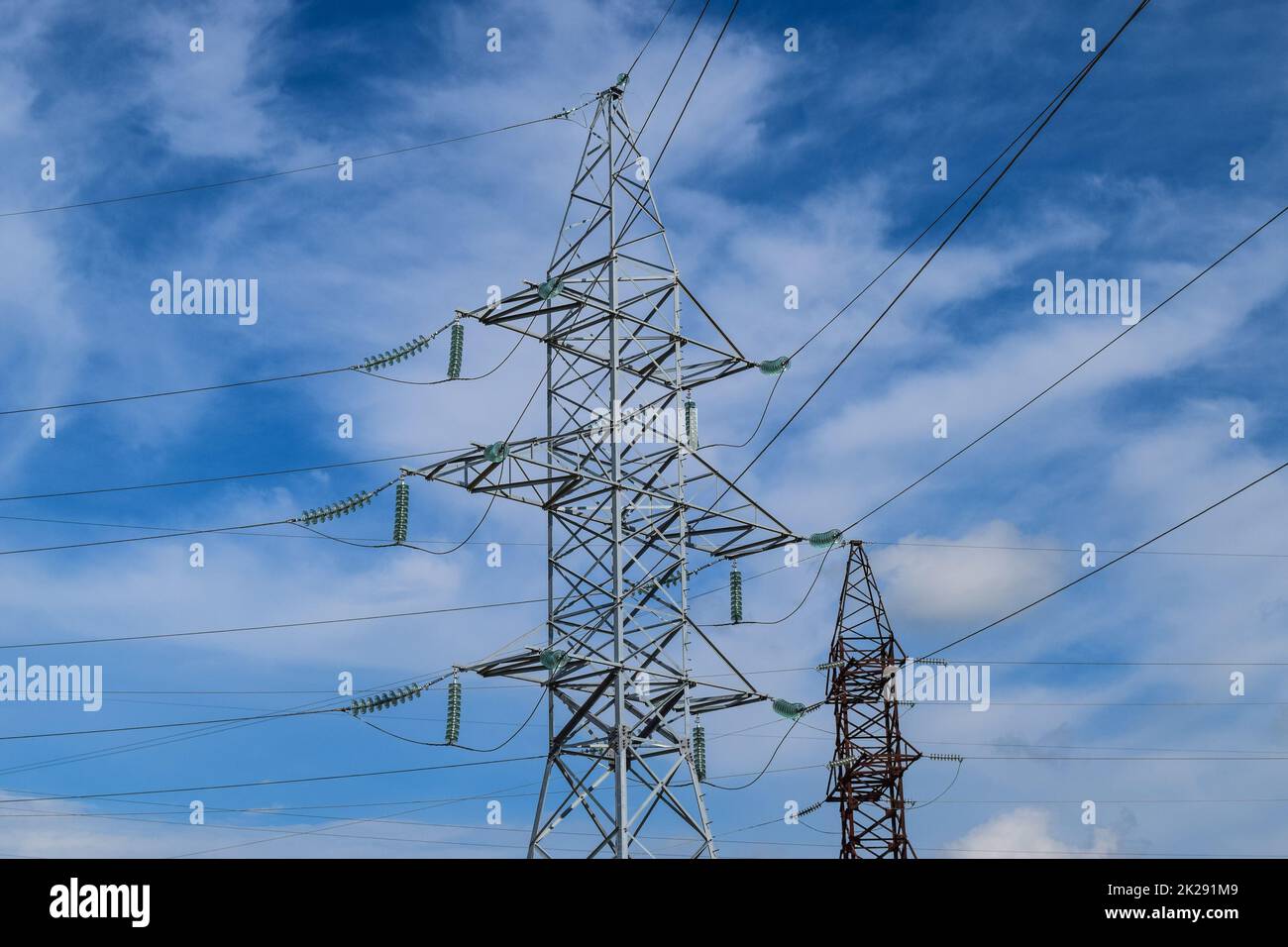 Supports high-voltage power lines against the blue sky with clouds ...