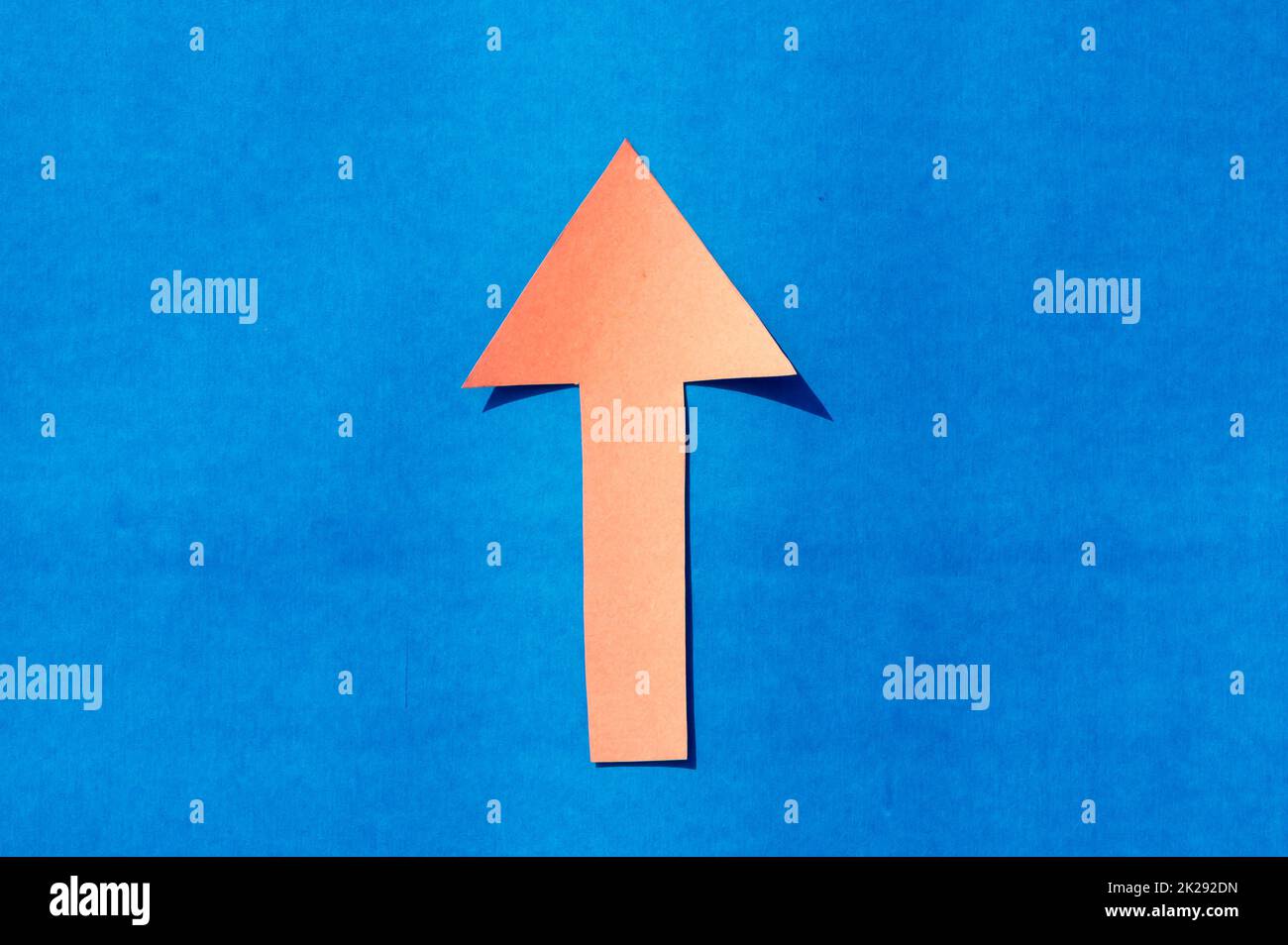 A up facing arrow symbol indicating upward direction. Isolated on blue background. Useful for signage and for way finding and surface markings. Stock Photo