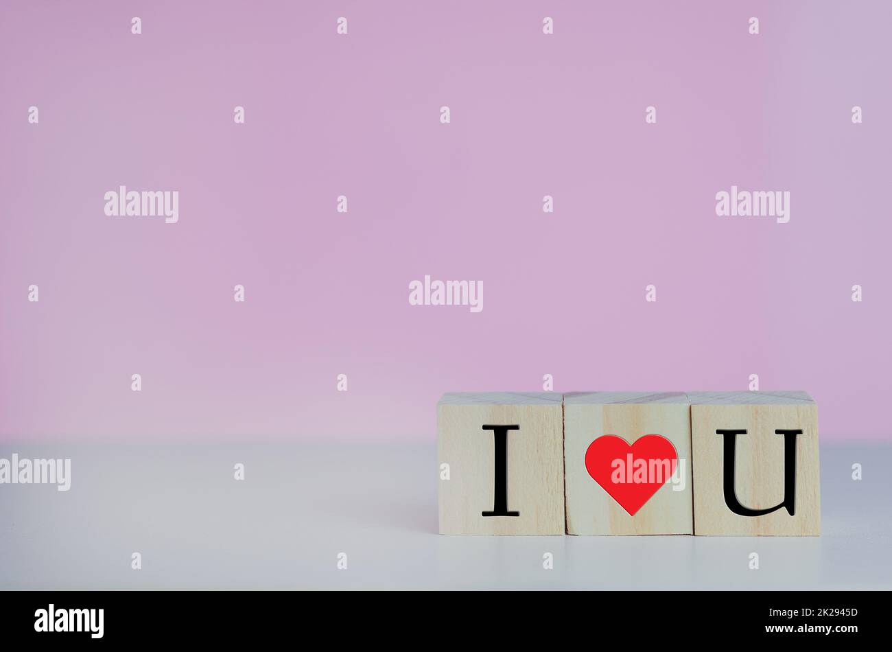 Wooden cubes with i love u symbol heart on the pink background and copy space. Stock Photo