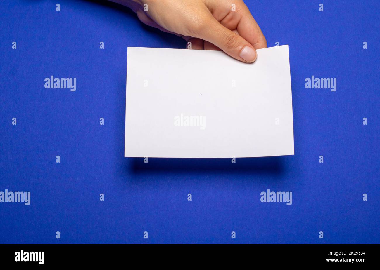 woman holding blank letter on blue colored background Stock Photo