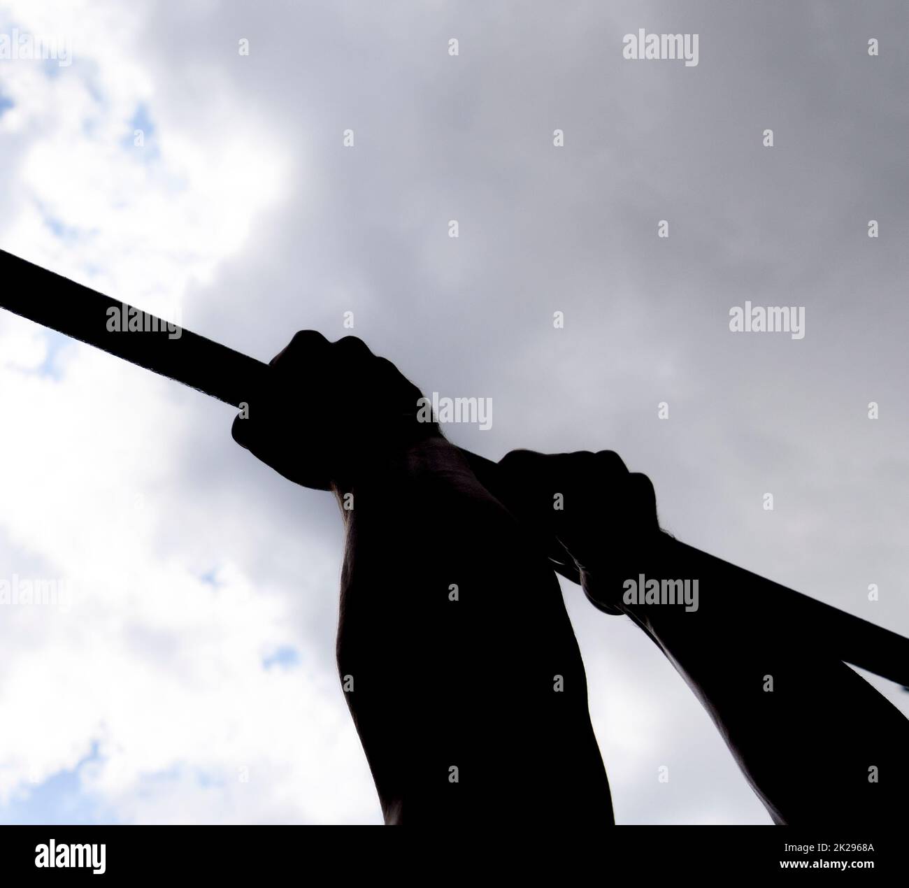 Silhouette of hands on a horizontal bar. Hands on the bar close-up. The man pulls himself up on the bar. Playing sports in the fresh air. Horizontal bar. Stock Photo