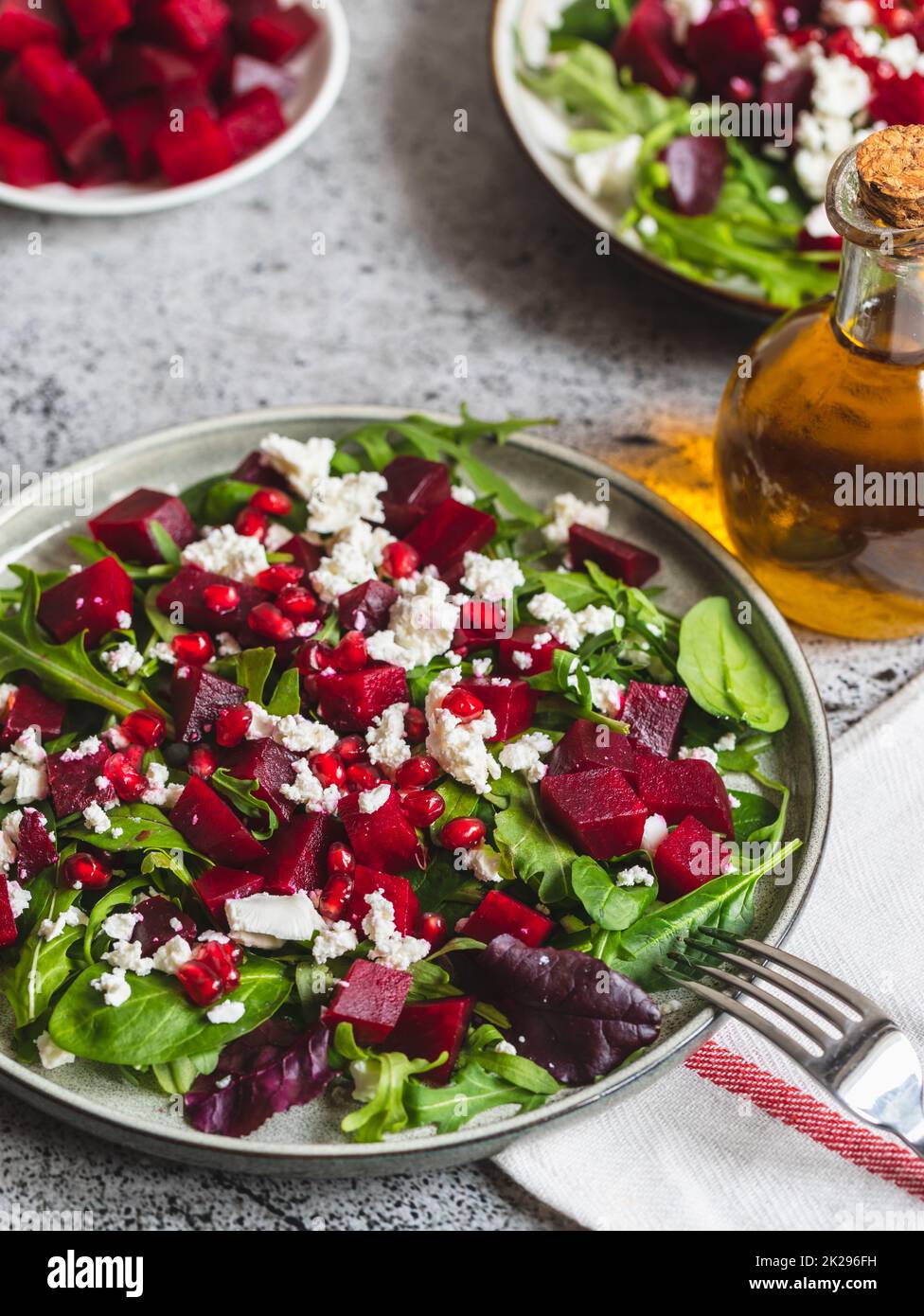 Arugula, Beet and cheese salad with pomegranate and dressing on plate on grey stone kitchen table background, place for text, top view Stock Photo